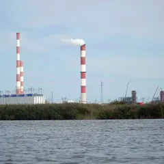 Widok na elektrownię Dolna Odra z dymiącym kominem i budynkami przemysłowymi na tle nieba.