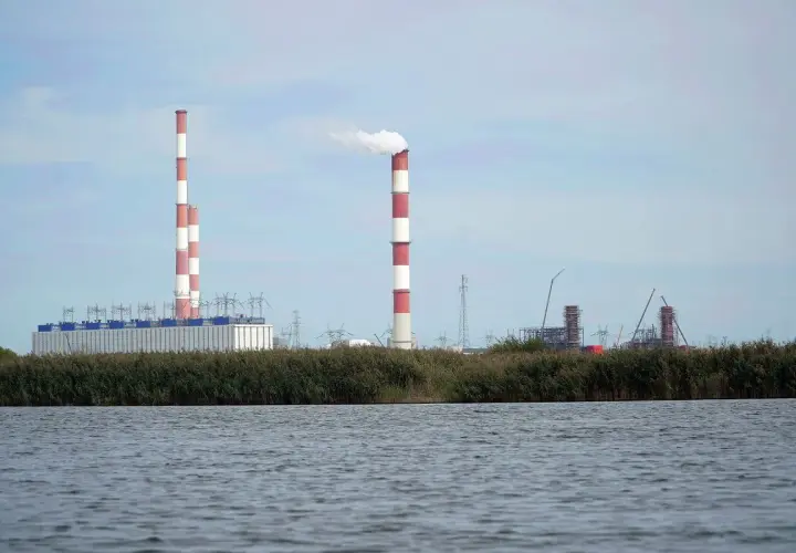 Widok na elektrownię Dolna Odra z dymiącym kominem i budynkami przemysłowymi na tle nieba.