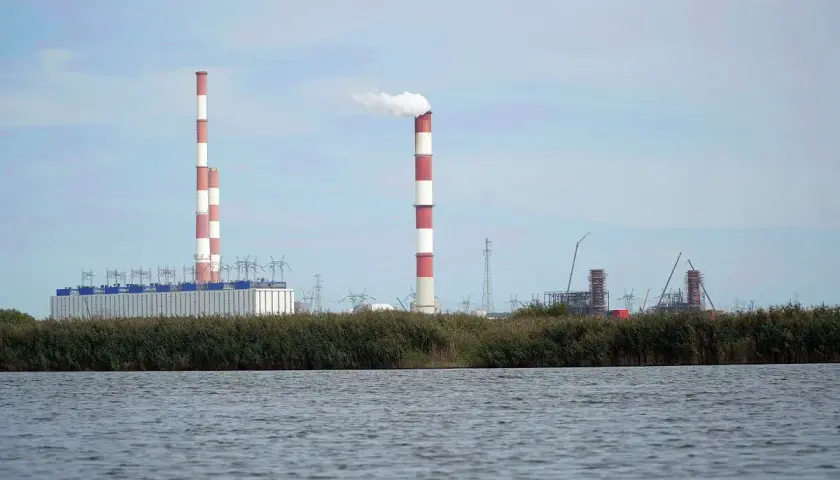 Widok na elektrownię Dolna Odra z dymiącym kominem i budynkami przemysłowymi na tle nieba.