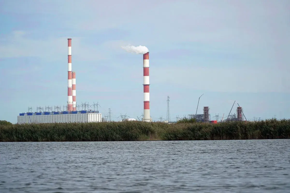 Widok na elektrownię Dolna Odra z dymiącym kominem i budynkami przemysłowymi na tle nieba.